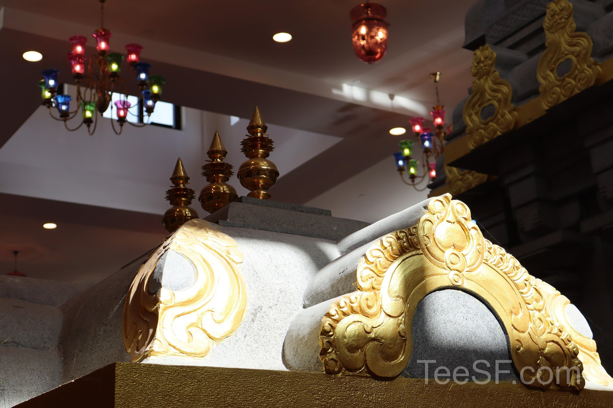 A temple ceiling view with warm lights and gold decorative forms.